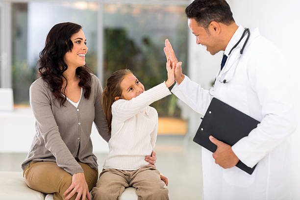 happy little girl and paediatrician doing high five after medical checkup